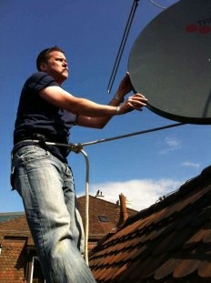 Techniker montiert eine Satellitenschüssel auf dem Dach